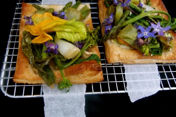 Spring vegetable and flower savory tart with goat cheese on oven rack