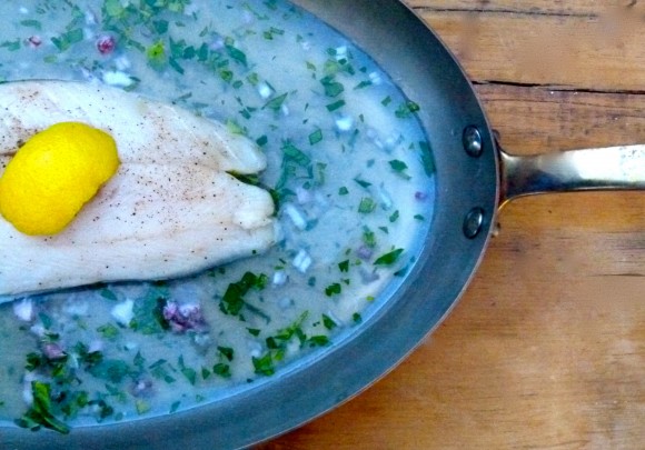 braising pan with cod fillet and lemon peel on top