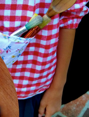 girl with paint brushes in pocket