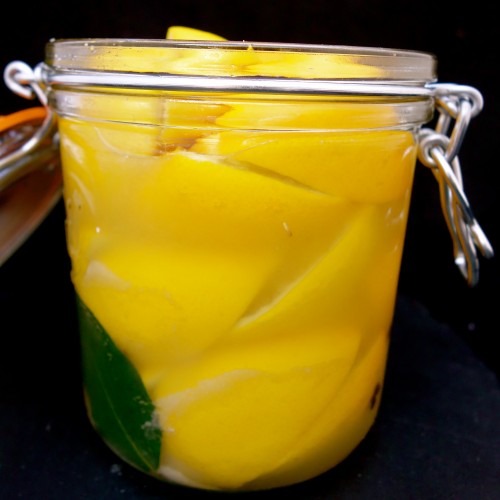 quartered and salted lemons with lemon juice in glass jar
